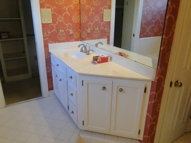 Old bathroom vanity with patterned wallpaper before renovation