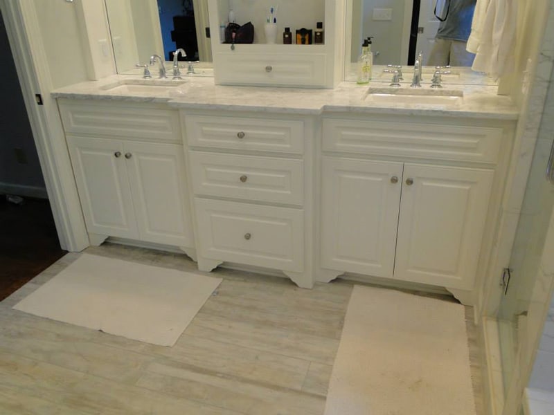 New white double vanity with a marble-tiled floor after renovation