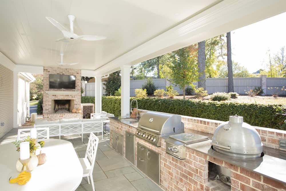 Covered outdoor living space with a brick fireplace and outdoor kitchen
