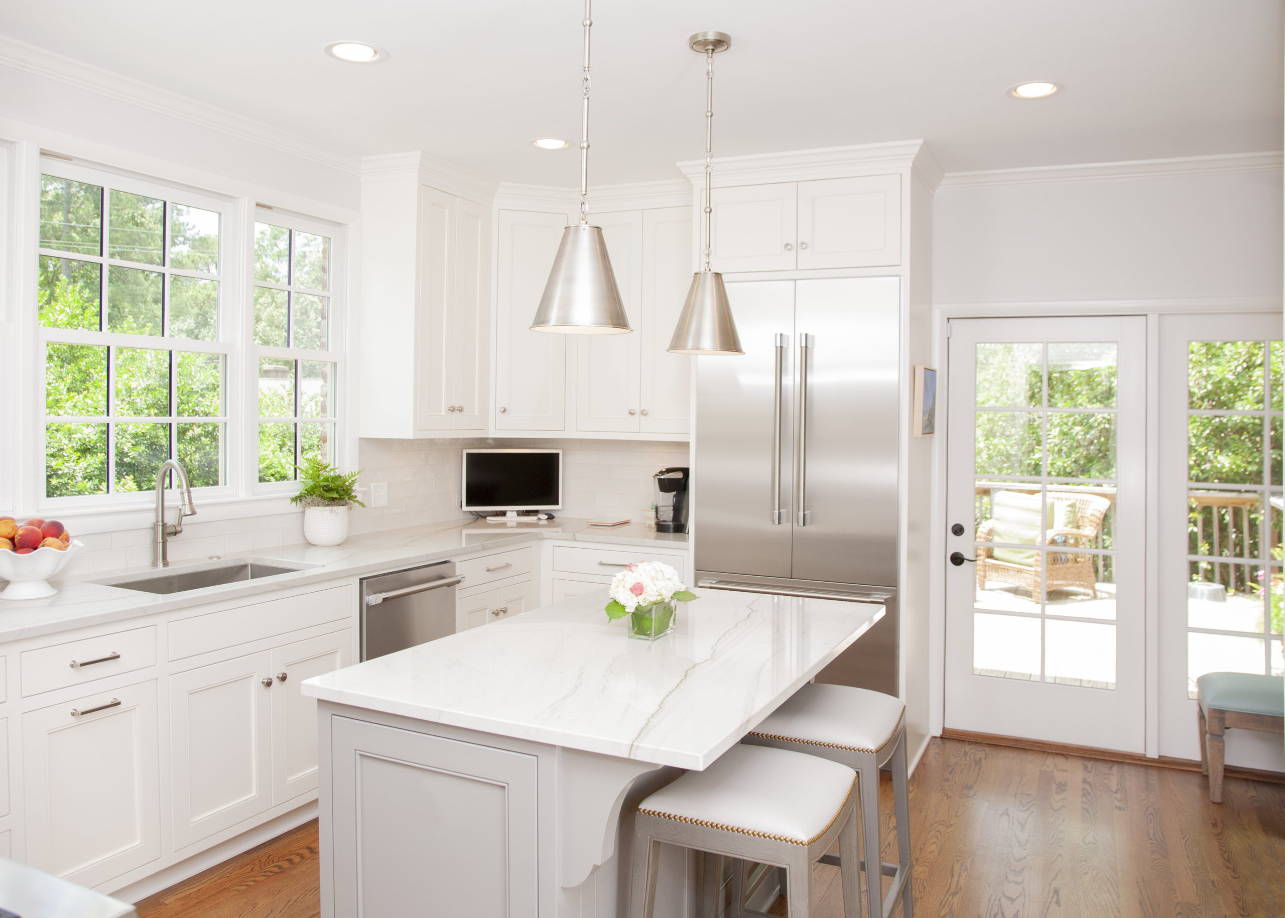 Bright white kitchen with a marble island and pendant lights