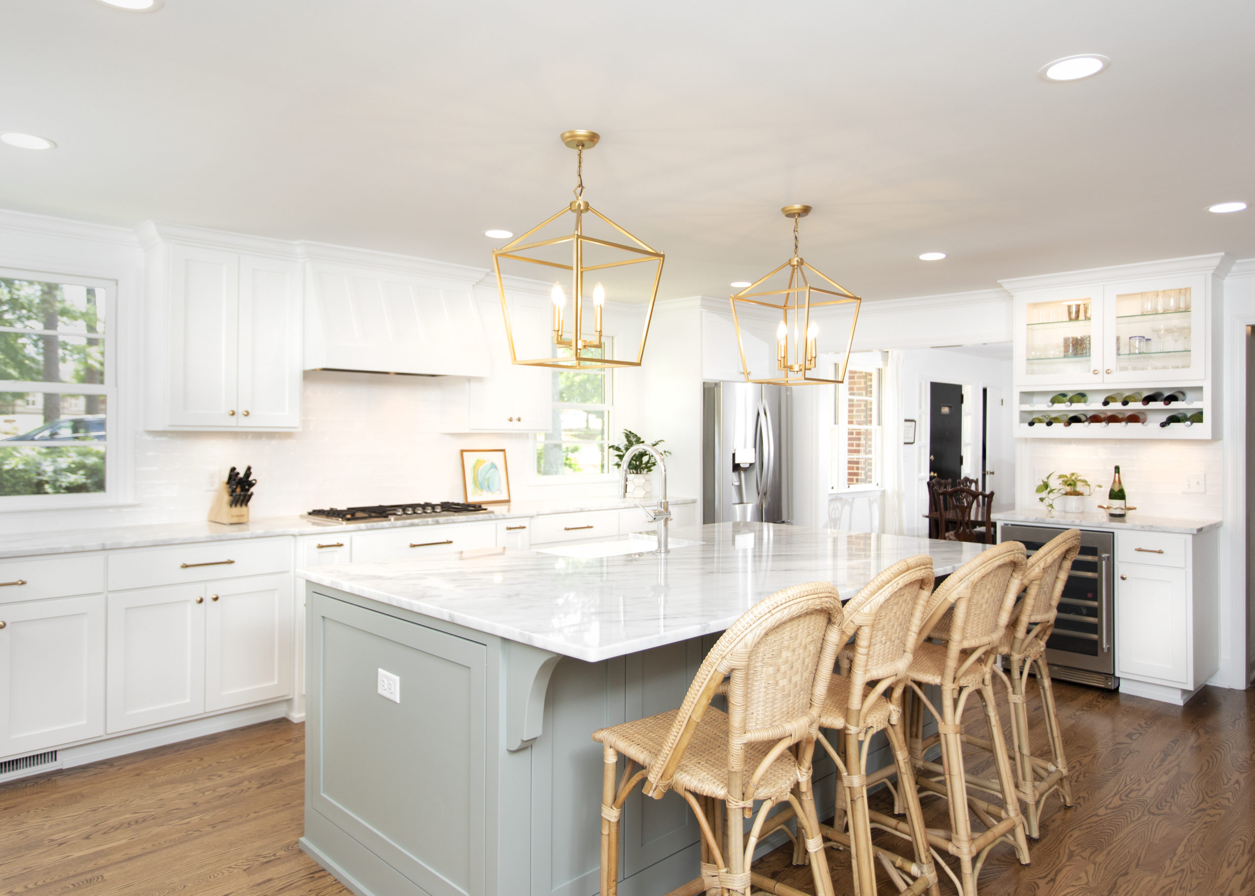 A bright, remodeled Columbia kitchen with a marble-topped island, woven counter stools and brass lantern pendants by Palmetto Construction & Renovations