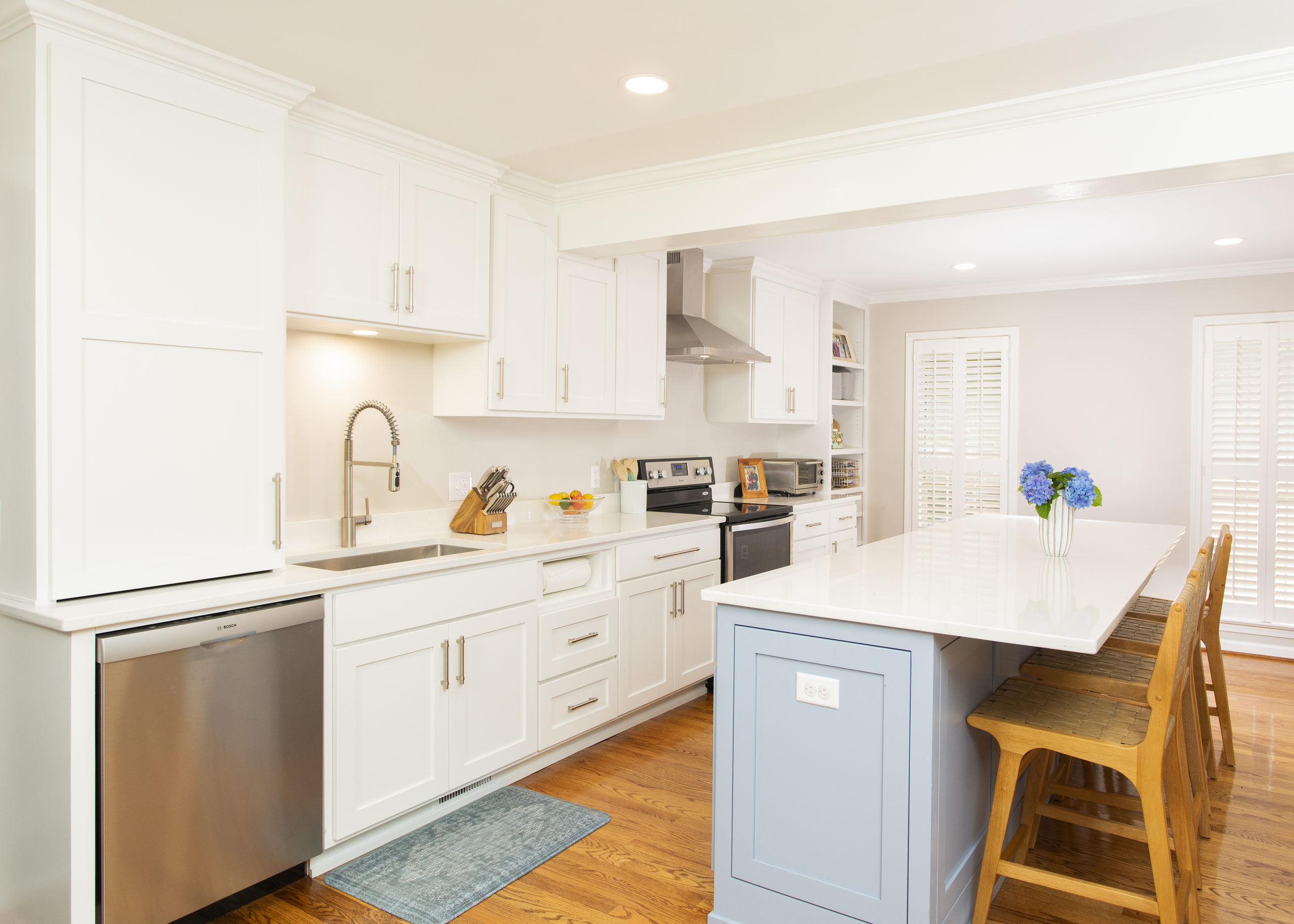 White kitchen with a blue island and farmhouse sink